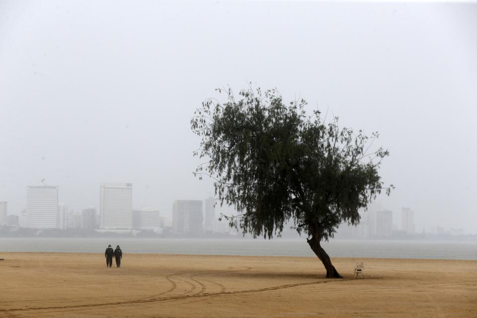 Police officers patrol a deserted beach before Cyclone Nisarga makes landfall in Mumbai, India, Wednesday, June 3, 2020. A storm in the Arabian Sea off India's west coast intensified into a severe cyclone on Wednesday, gathering speed as it barreled toward India's financial capital of Mumbai. Nisarga was forecast to drop heavy rains and winds gusting up to 120 kilometers (75 miles) per hour when it makes landfall Wednesday afternoon as a category 4 cyclone near the coastal city of Alibagh, about 98 kilometers (60 miles) south of Mumbai, India's Meteorological Department said. (AP Photo/Rajanish Kakade)