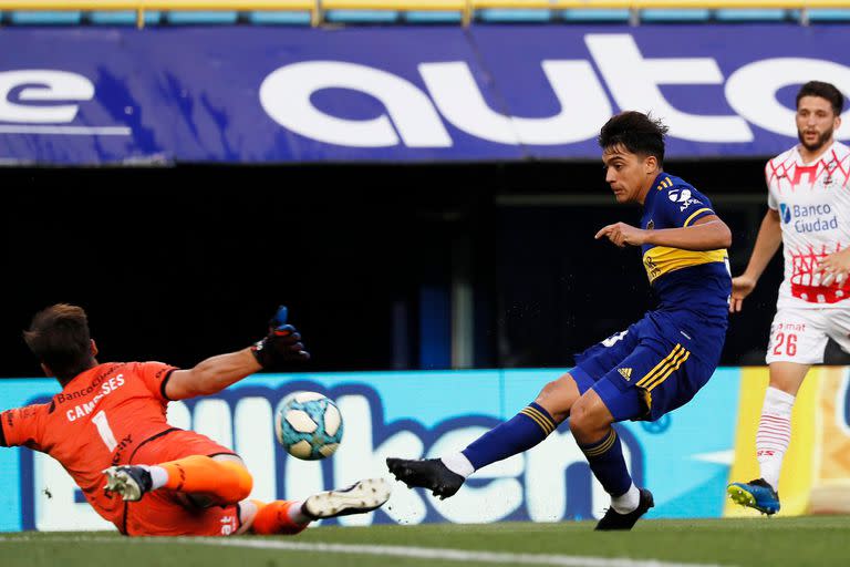 Exequiel Zeballos patea ante la salida de Facundo Cambeses durante el partido que disputan Boca Juniors y Huracán.