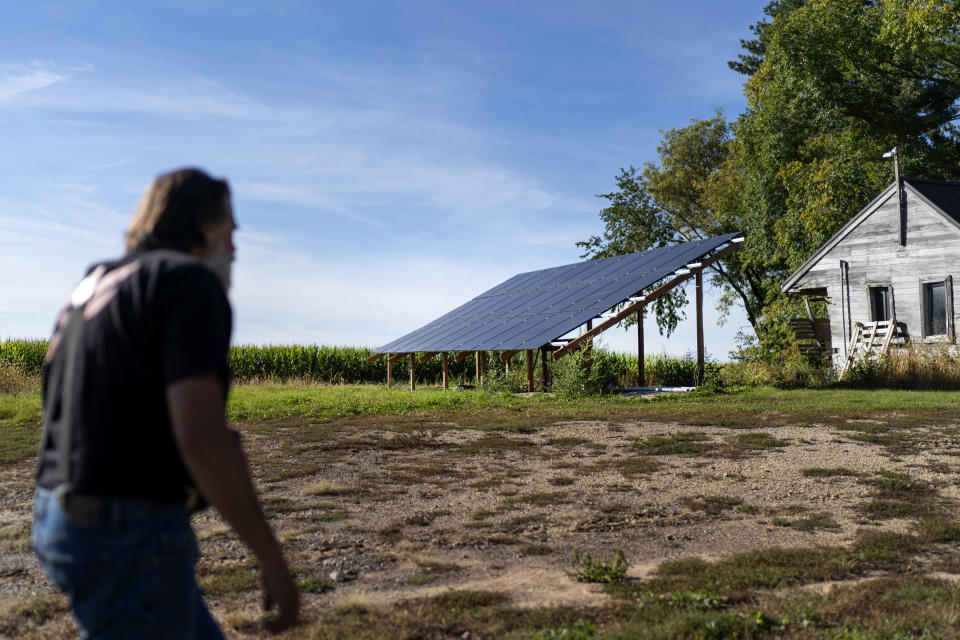 John Kraft pasa frente a los paneles solares que está conectando a su casa en Clear Lake, Wisconsin, el 28 de septiembre de 2022. Por temor a una falla en la red eléctrica, los conservadores de derecha a menudo hablan de instalar sistemas solares en sus hogares. Planes como este, si es que se mencionan, se hablan en voz baja, pero siéntese en suficientes bares de pueblos pequeños y maneje suficientes caminos de tierra y ocasionalmente escuchará a la gente hablar sobre lo que pretenden hacer si las cosas se ponen realmente mal para Estados Unidos. (AP Foto/David Goldman)