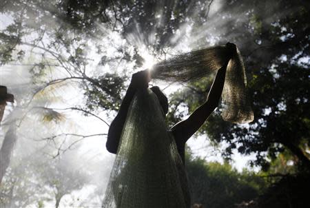 Francisco Estrada, a friend of castaway fisherman Jose Salvador Alvarenga, spreads out a fishing net in the fishing town of Ahuchapan, Alvarenga's hometown, February 4, 2014. REUTERS/ Ulises Rodriguez