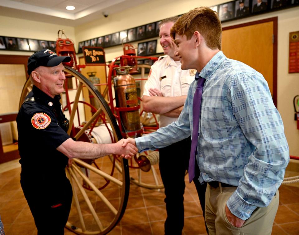 Craig Scharland, 18, of Franklin, right, shakes hands with Franklin fire Capt. Darrel Griffin, as Battalion Chief Chuck Allen looks on, May 26, 2022. Scharland was recently reunited with the firefighters who helped deliver him almost 19 years ago, at Franklin Fire Department headquarters. Scharland will graduate from Bishop Feehan High School on June 3.
