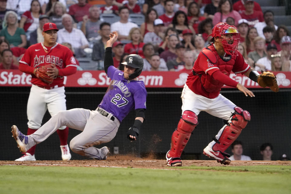 Colorado Rockies' Trevor Story, center, scores on a single by Ryan McMahon as Los Angeles Angels catcher Kurt Suzuki, right, waits for the ball as starting pitcher Jose Suarez backs him up during the third inning of a baseball game Tuesday, July 27, 2021, in Anaheim, Calif. (AP Photo/Mark J. Terrill)
