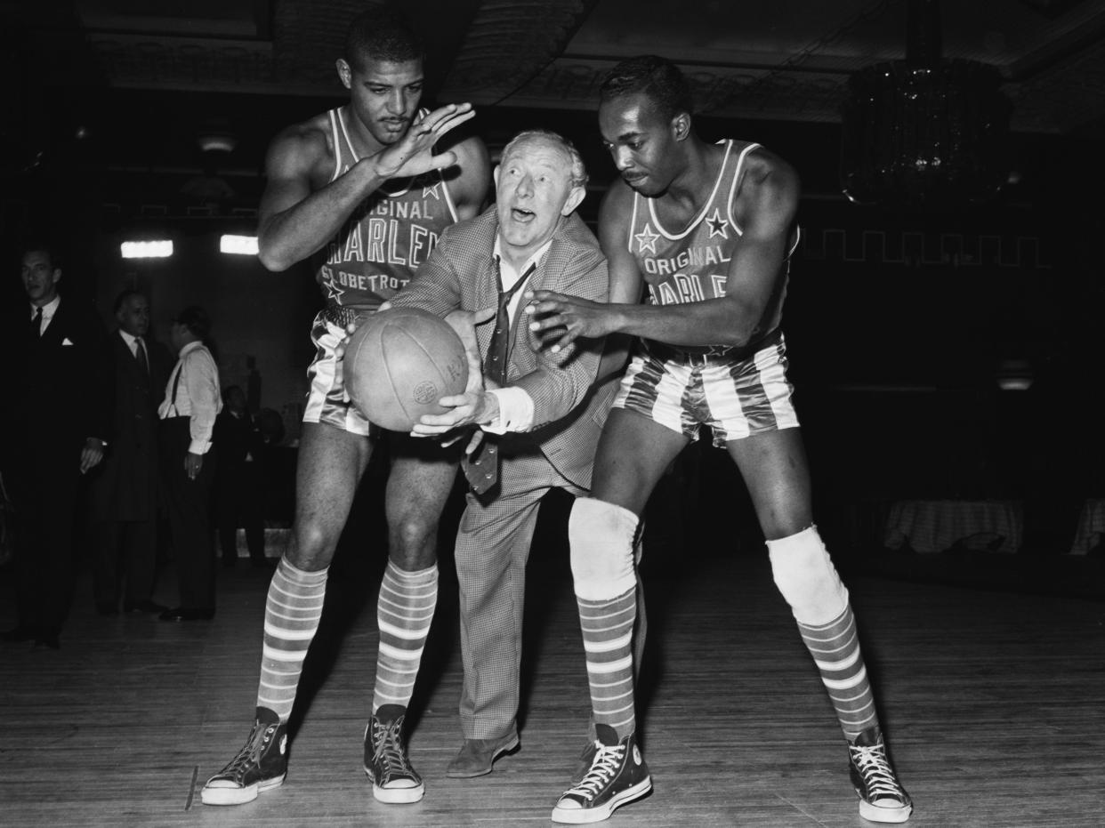 British comedian and actor Richard Hearne tries to play basketball with Harlem Globetrotters J Walter Kennedy and Murphy Simmons in 1963.