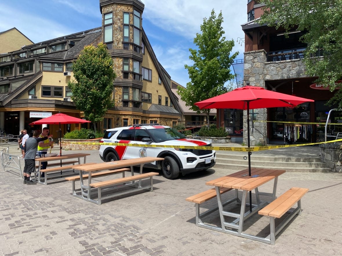 A paramedic vehicle sits behind police tape outside storefronts in Whistler, B.C., on Sunday afternoon. (Jessica Cheung/CBC - image credit)