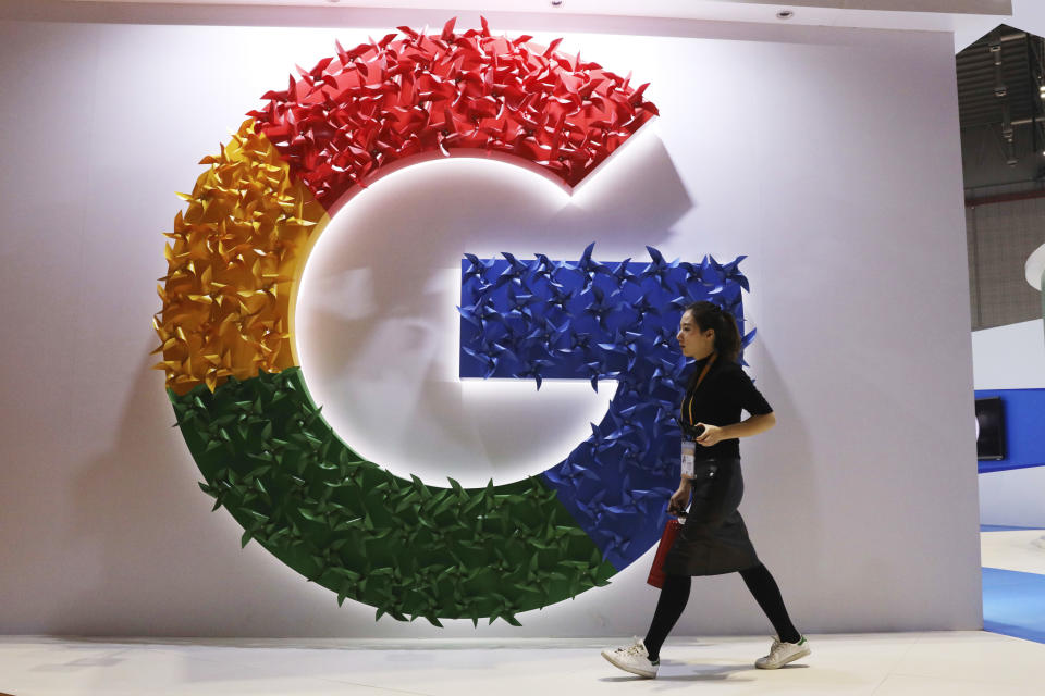 FILE - In this Monday, Nov. 5, 2018 file photo, a woman walks past the logo for Google at the China International Import Expo in Shanghai. Google says it will start giving European Union smartphone users a choice of browsers and search apps on its Android operating system. The changes are designed to comply with an EU antitrust ruling. The U.S. internet giant said Thursday, April 18, 2019 that following an Android update, users will be shown two new screens giving them the option install up to five search apps and five browsers. (AP Photo/Ng Han Guan)