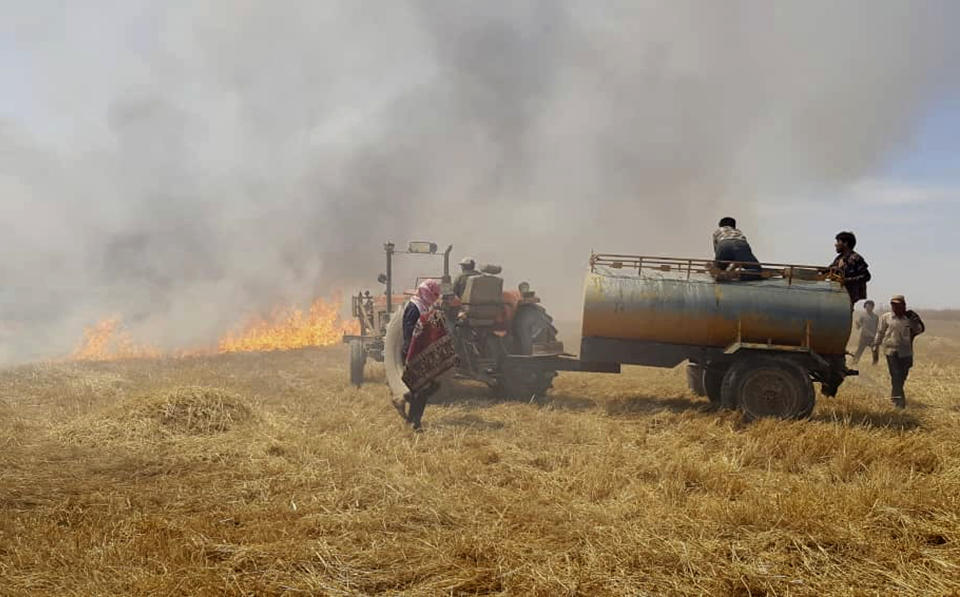 This Tuesday, May 28, 2019 photo, provided by the community service group, Together for Jarniyah, which has been authenticated based on its contents and other AP reporting, shows Syrians working to extinguish a fire in a field of crops, in Jaabar, Raqqa province, Syria. Crop fires in parts of Syria and Iraq have been blamed on defeated Islamic State group militants in the east seeking to avenge the group’s losses, and on Syrian government forces in the west battling to rout other armed groups there. (Together for Jarniyah via AP)