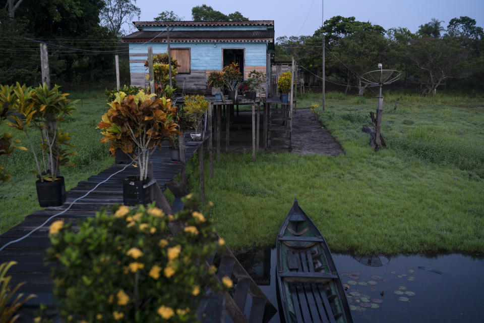 In this Nov. 22, 2019 photo, a wooden house stands at dawn in the Renascer Reserve in the Amazon rainforest in Prainha, Para state, Brazil. The clock is ticking. Already the Amazon is growing warmer and drier, losing its capacity to recycle water, and may become savannah in 15 to 30 years, said Carlos Nobre, a climate scientist at the University of Sao Paulo. (AP Photo/Leo Correa)
