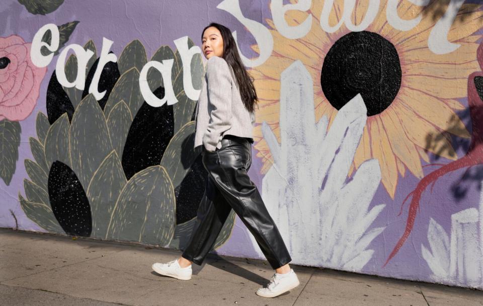 Woman in a business suit walking and looking back in front of a mural