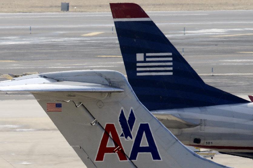 FILE - In this Thursday, Feb. 14, 2013, file photo, American Airlines and US Airways jets prepare for flight at a gate at the Philadelphia International Airport in Philadelphia. The Justice Department and a number of state attorneys general on Tuesday, Aug. 13, 2013, challenged a proposed $11 billion merger between US Airways Group Inc. and American Airlines' parent company, AMR Corp. (AP Photo/Matt Rourke, File)