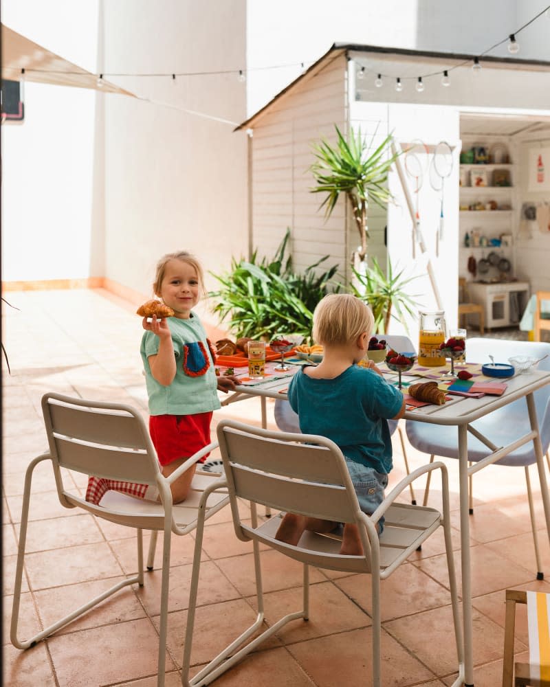 2 kids having breakfast at table on outdoor tile patio