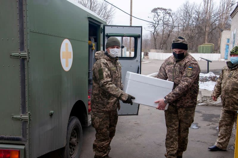 FILE PHOTO: Ukrainian servicemen carry a box with the Oxford-AstraZeneca vaccine in Donetsk Region