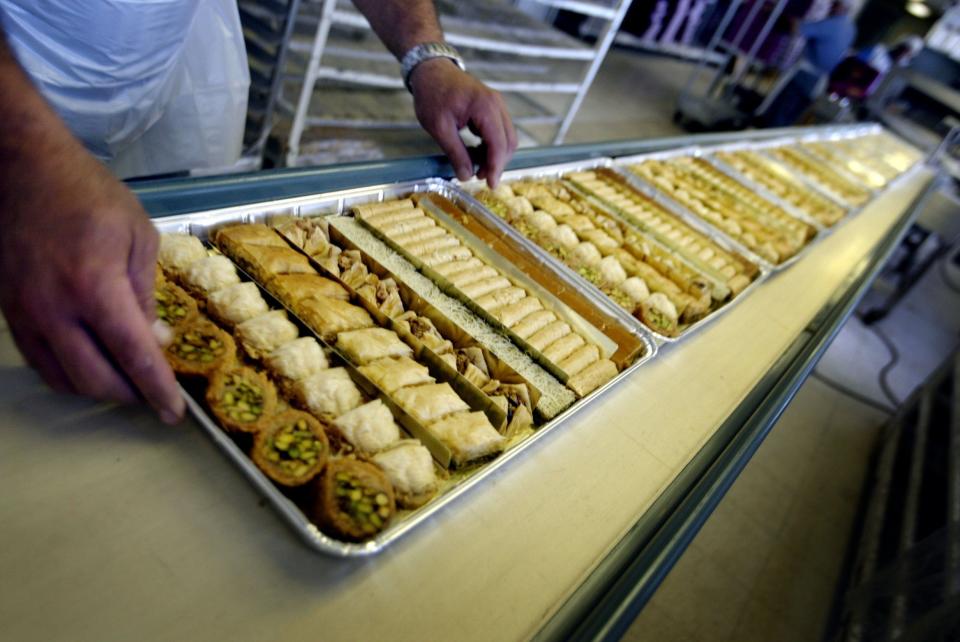 Trays of pastries are put on the conveyor belt of a packaging machine at Shatila, a fabric of Mediterranean-MidEast pastries in Dearborn.