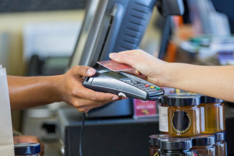 Woman's hand scanning loyalty card at EFTPOS machine, held by man's arm