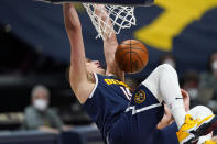 Denver Nuggets center Nikola Jokic hangs from the rim after dunking against the San Antonio Spurs in the second half of an NBA basketball game Friday, April 9, 2021, in Denver. (AP Photo/David Zalubowski)