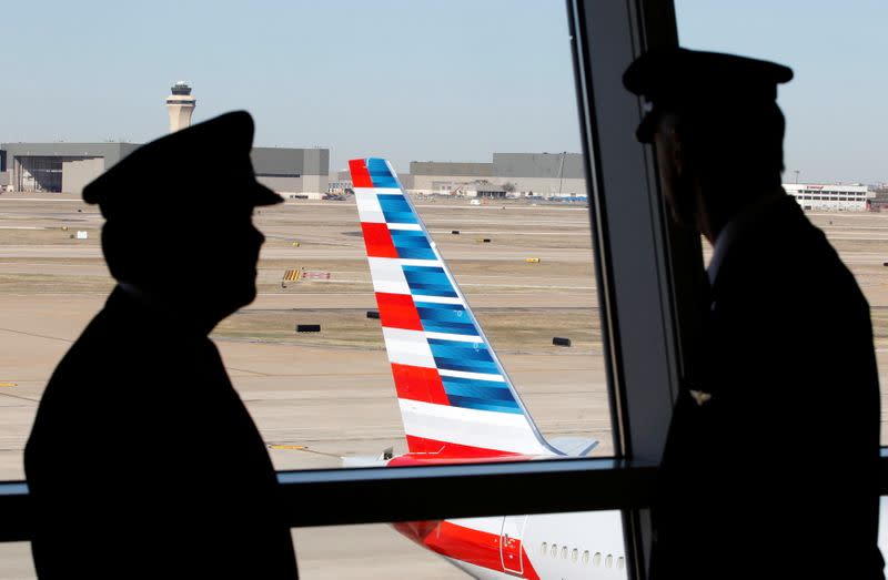 FILE PHOTO: Pilots talk as they look at the tail of an American Airlines aircraft f at Dallas-Ft Worth International Airport