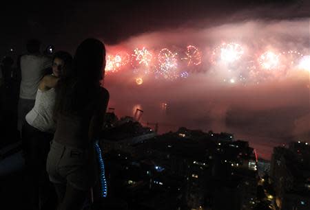 People watch fireworks exploding over Copacabana beach during New Year celebrations at the Pavao Pavaozinho slum in Rio de Janeiro