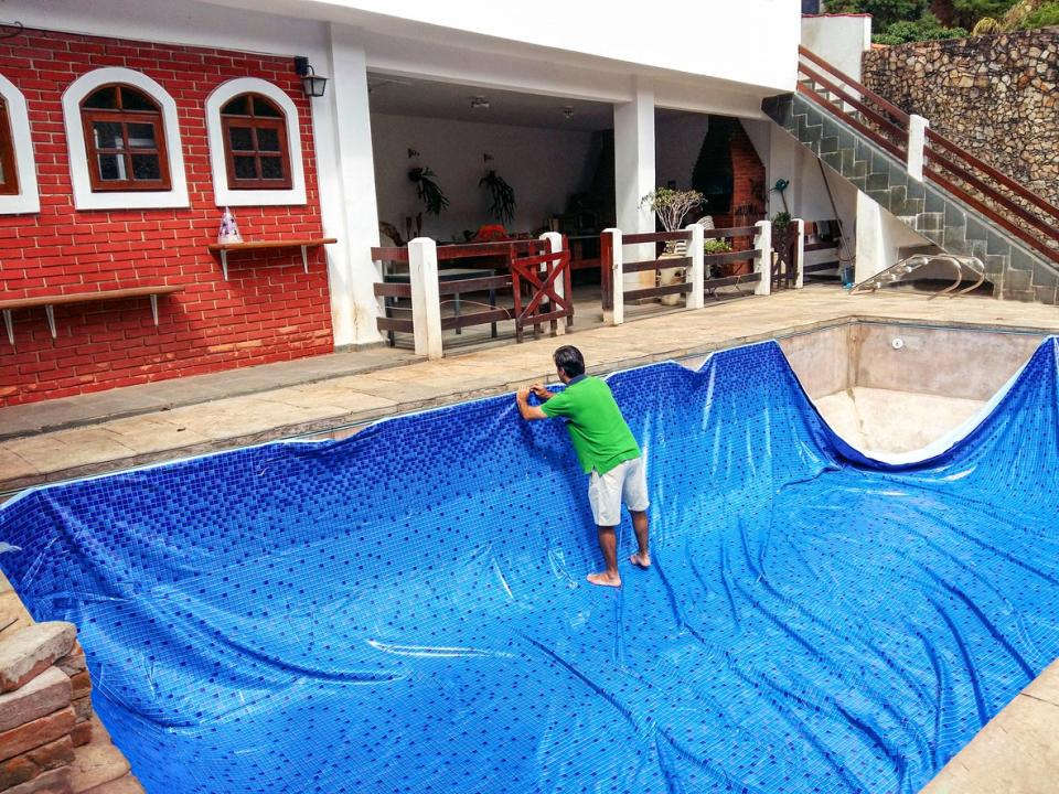 A man in a green shirt is in the process of building a pool.