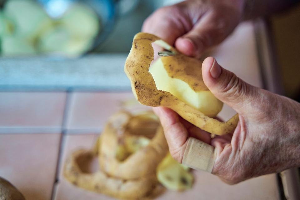 mature hands peeling a potato