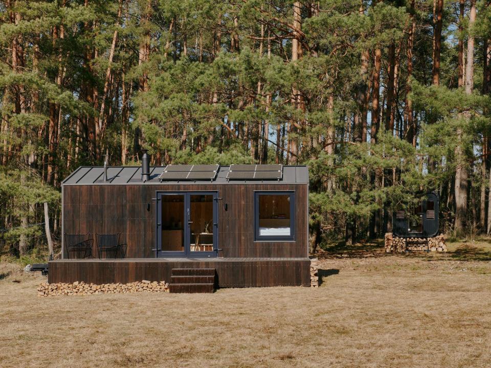 A Raus cabin in nature surrounded by trees and open fields.