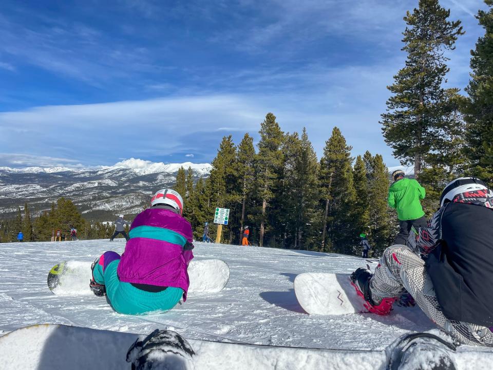 The author rests and straps into her snowboard.