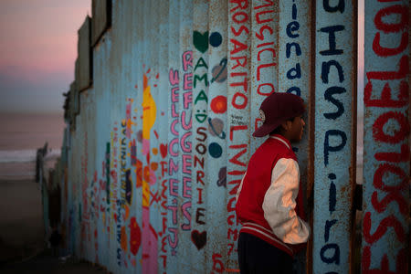 Angel, a 13-year-old migrant from Honduras, part of a caravan of thousands from Central America trying to reach the U.S., looks towards the United States past the border fence in Tijuana, Mexico November 15, 2018. REUTERS/Adrees Latif