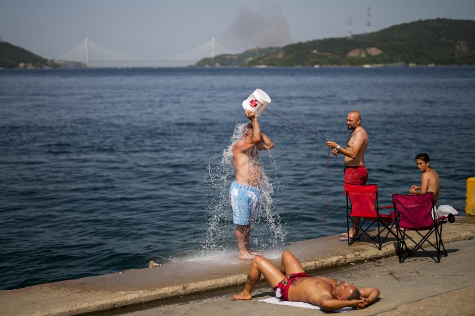 FILE - People cool off at the Bosphorus as a forest fire smoke rises, background, during a hot summer day in Istanbul, Turkey, July 26, 2023. Earth last year shattered global annual heat records, the European climate agency said Tuesday, Jan. 9, 2024. (AP Photo/Francisco Seco, File)