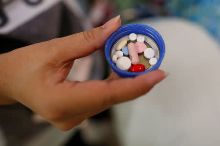 Supapan Pullbangyung, 39, holds a cup containing medicines for her father, Serm Pullbangyung, 75, at her house in Nonthaburi, Thailand, April 24, 2016. REUTERS/Athit Perawongmetha