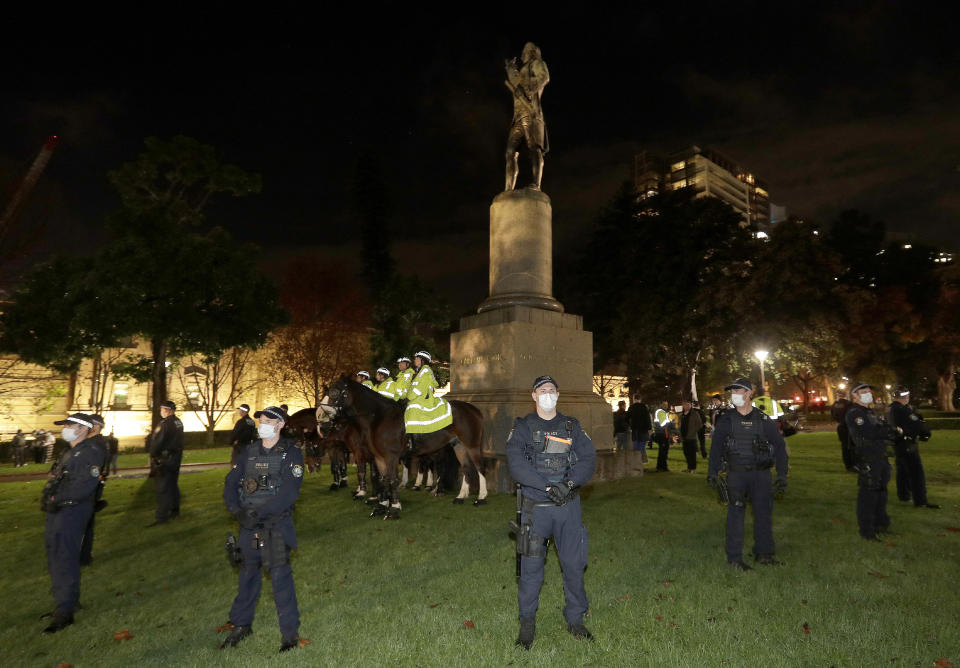 Police guard a statue of British explorer James Cook as protesters gather in Sydney, Friday, June 12, 2020, to support U.S. protests over the death of George Floyd. Hundreds of police disrupted plans for a Black Lives Matter rally but protest organizers have vowed that other rallies will continue around Australia over the weekend despite warnings of the pandemic risk. (AP Photo/Rick Rycroft)