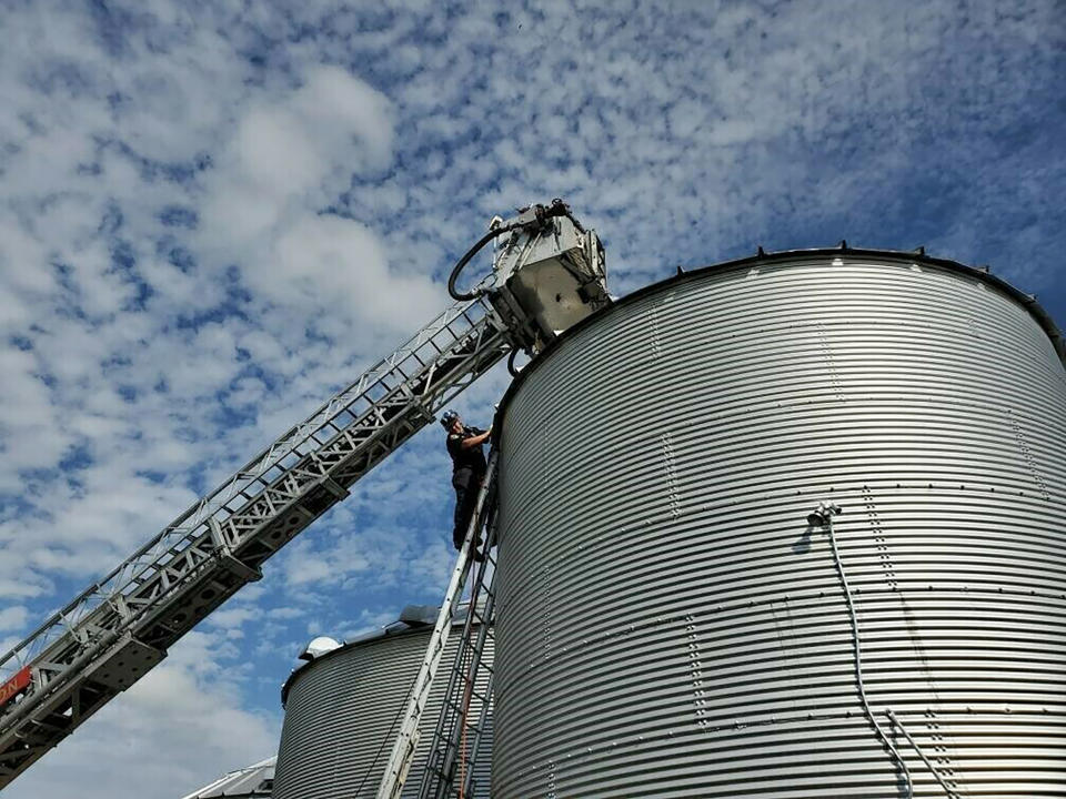 In this May 30, 2019 photo provided by the Ross Township Fire Department a fire truck bucket hovers over a bin where farmer Jay Butterfield became buried up to his neck in soybeans. The successful rescue effort in Ross Township, Ohio, involved 52 rescue personnel from a dozen agencies. (Ross Township Fire Department via AP)