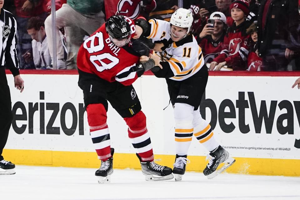 Boston Bruins' Trent Frederic (11) punches New Jersey Devils' Kevin Bahl (88) during the first period of an NHL hockey game Wednesday, Dec. 28, 2022, in Newark, N.J. (AP Photo/Frank Franklin II)