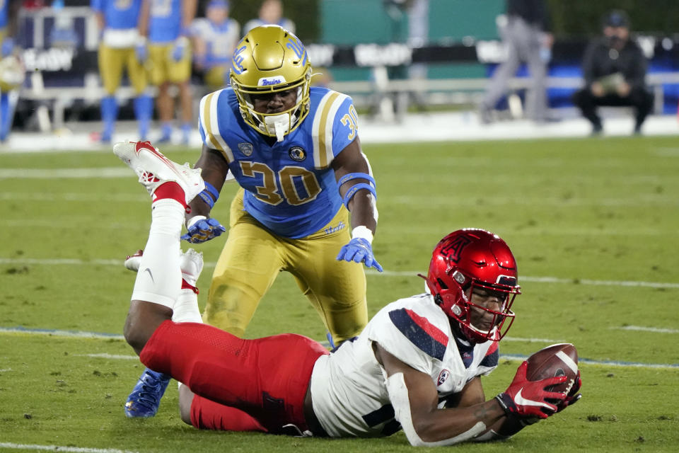 Arizona wide receiver Jamarye Joiner, bottom, makes catch in front of UCLA defensive back Elisha Guidry (30) during the second half of an NCAA college football game Saturday, Nov. 28, 2020, in Pasadena, Calif. (AP Photo/Marcio Jose Sanchez)