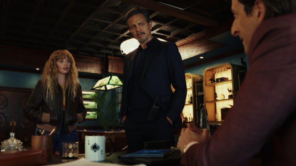 Natasha Lyonne and Benjamin Bratt look towards Adrien Brody's desk in Poker Face.