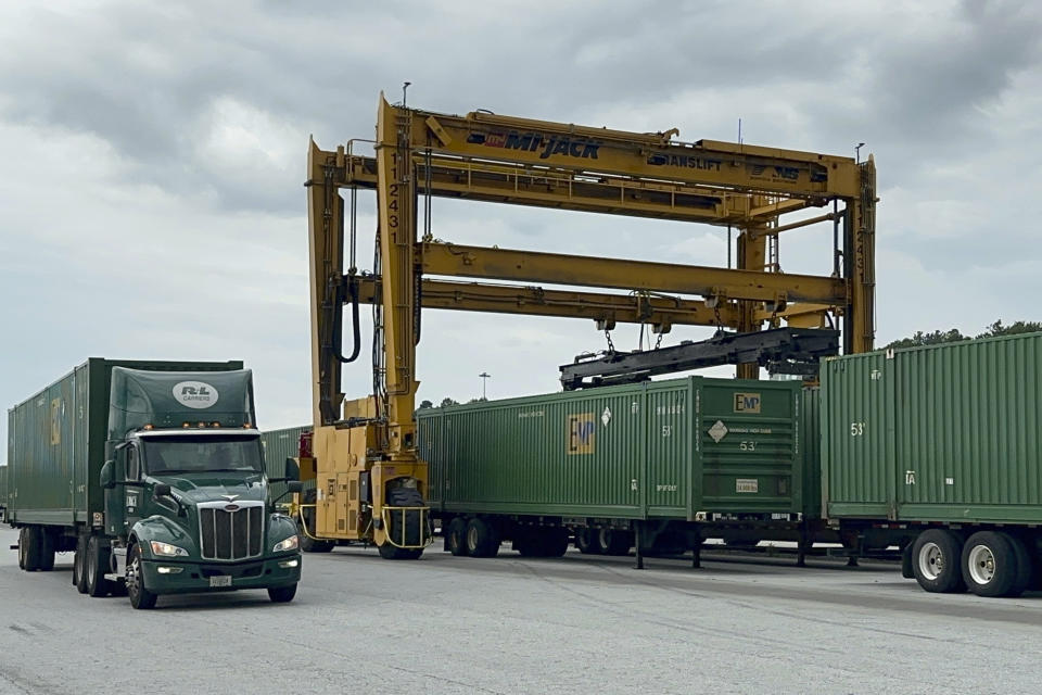 A truck pulls a trailer loaded with a shipping container away from a Norfolk Southern rail yard in the Atlanta area on June 20, 2023, after it was unloaded from a train. (AP Photo/Josh Funk)