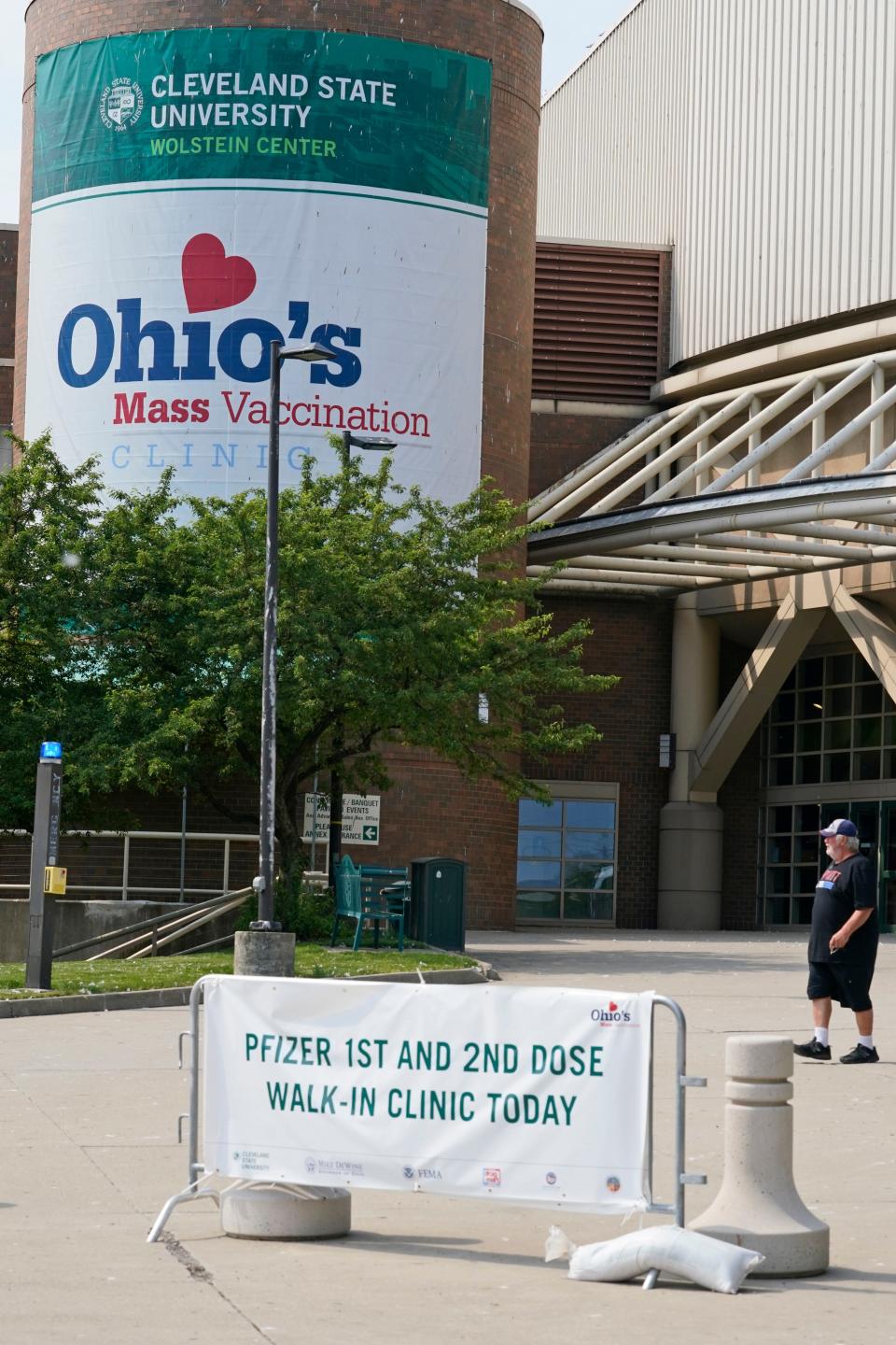 A man walks by signs for Ohio's COVID-19 mass vaccination clinic at Cleveland State University, Tuesday, May 25, 2021, in Cleveland.