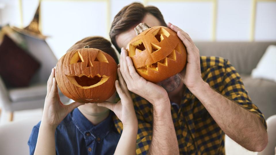 dad and son holding jack o lanterns to their faces