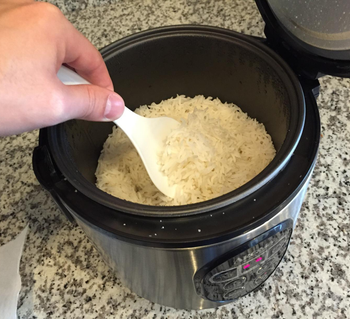 The rice cooker with cooked rice in it 