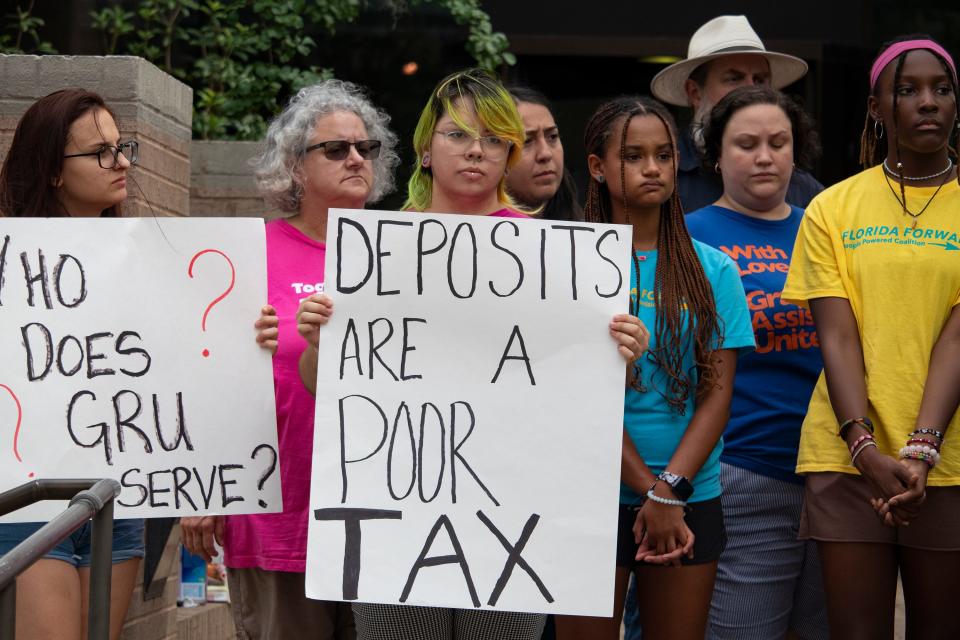 Attendees holds signs during a press conference hosted by Community Leaders United at the Gainesville Regional Utilities building downtown on Aug. 25.