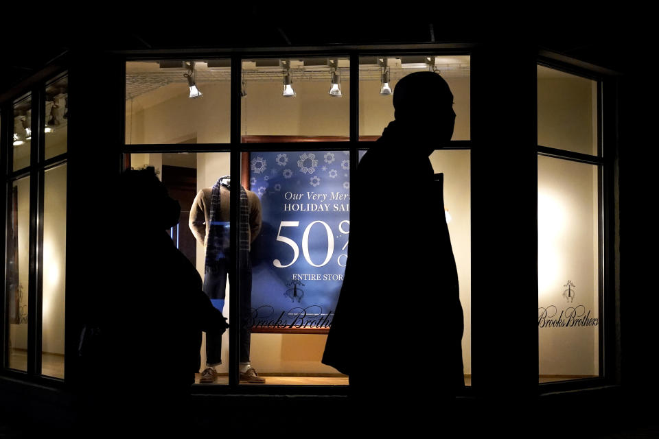 FILE - In this Saturday, Dec. 19, 2020 file photo, people walk past the window display of a store in Skokie, Ill. A closely-watched gauge for U.S. consumer confidence released on Tuesday, Dec. 22, 2020, tumbled to a reading of 88.6 in December as rising coronavirus cases tamped down American optimism to its lowest level since summer. (AP Photo/Nam Y. Huh)