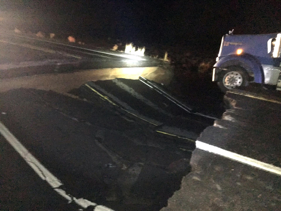 This photo provided by the Arizona Department of Public Safety shows a semi truck stuck in a large sinkhole on Highway US 89 near Cameron, Ariz., after heavy rains hit the area Wednesday, Oct. 3, 2018. The Arizona Department of Transportation said that troopers discovered the large hole when they responded to an incident late Wednesday night. (Arizona Department of Public Safety via AP)
