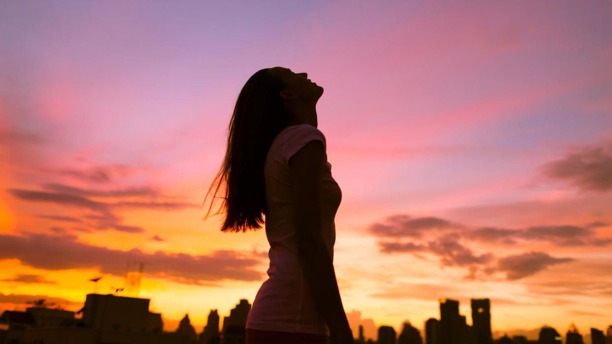 Happy woman in the city looking up into the sky.