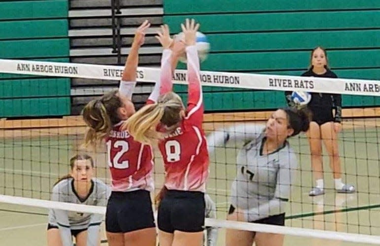Ally Younglove (12) and Adi Simmons put up a block for Monroe during a volleyball five-set win over Ann Arbor Huron Tuesday night.
