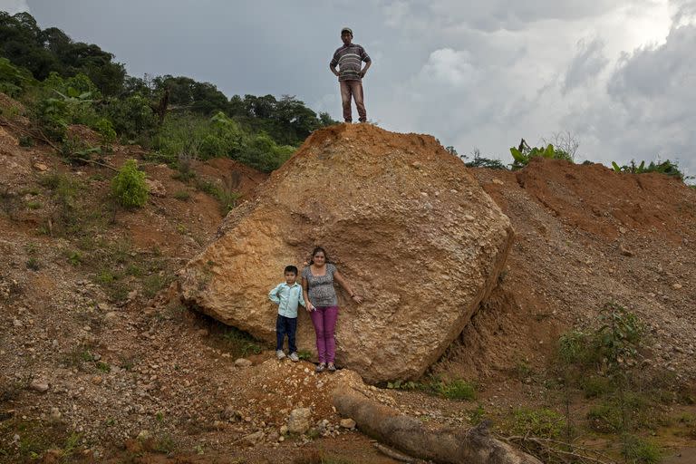 Elvia Gutiérrez, 46 años; su hijo, Jonathan Portillo, de 6 años; y su esposo, Santos Portillo, de 50 años, posan para un retrato en el sitio donde su casa fue destruida por un deslizamiento de tierra provocado por los huracanes Eta e Iota en el pueblo de La Reina, Honduras 