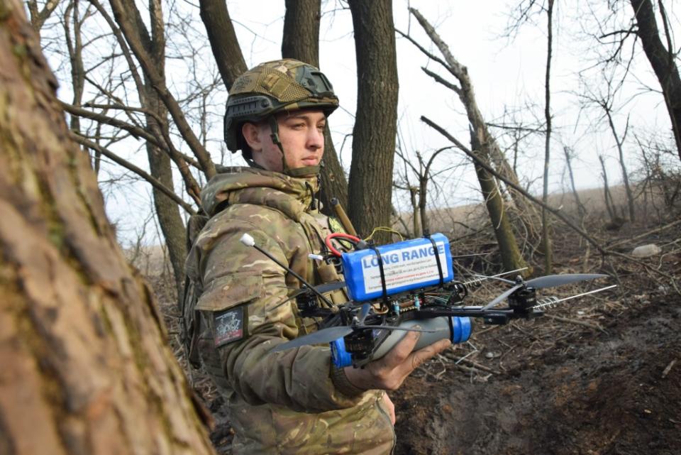 A soldier holds an armed FPV drone, ready to take off. (Photo via Bennett Murray)