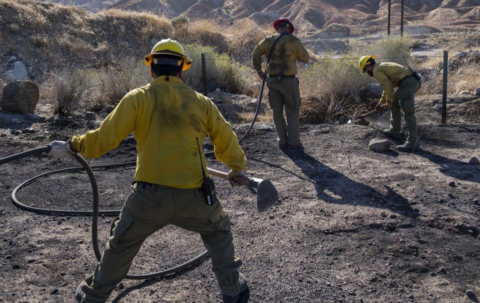 An engine crew looks for any remaining hot spots from the Tick Fire, Thursday, Oct. 25, 2019, in Santa Clarita, Calif. An estimated 50,000 people were under evacuation orders in the Santa Clarita area north of Los Angeles as hot, dry Santa Ana winds howling at up to 50 mph (80 kph) drove the flames into neighborhoods (AP Photo/ Christian Monterrosa)