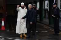 A man gestures as Police officers are seen outside the London Central Mosque in London