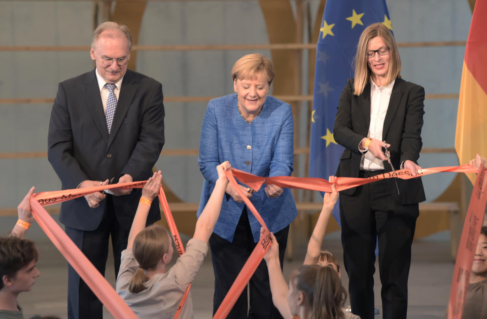 German Chancellor Angela Merkel, center, Claudia Perren, director and chief executive officer of the Bauhaus Dessau Foundation, right, and Reiner Haseloff, governor of the German state of Saxony-Anhalt cut the rope during the official opening of the new Bauhaus Museum, built for the centenary of the founding of the Bauhaus, in Dessau, Germany Sunday, Sept. 8, 2019. (AP Photo/Jens Meyer)