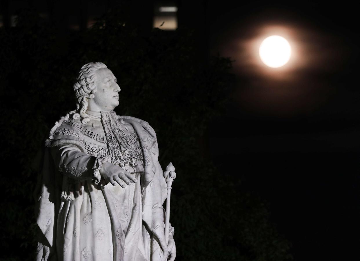 A statue of King Louis XVI had a view of the April Pink Moon in downtown Louisville, Ky., April 7, 2020.