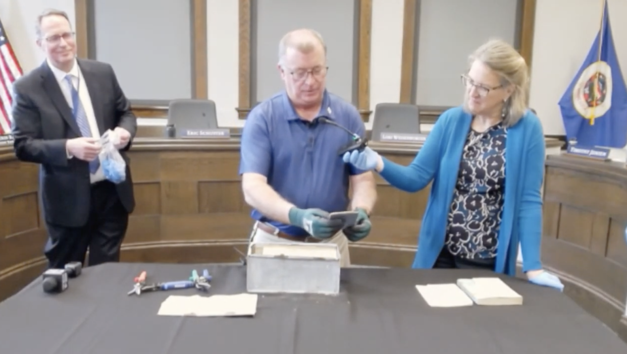 Owatonna Public Schools Director of Facilities, Infrastructure and Security Bob Olson carefully removes documents from a time capsule dated 1920 that was found during the demolition of an old high school site.  / Credit: Owatonna Public Schools via YouTube