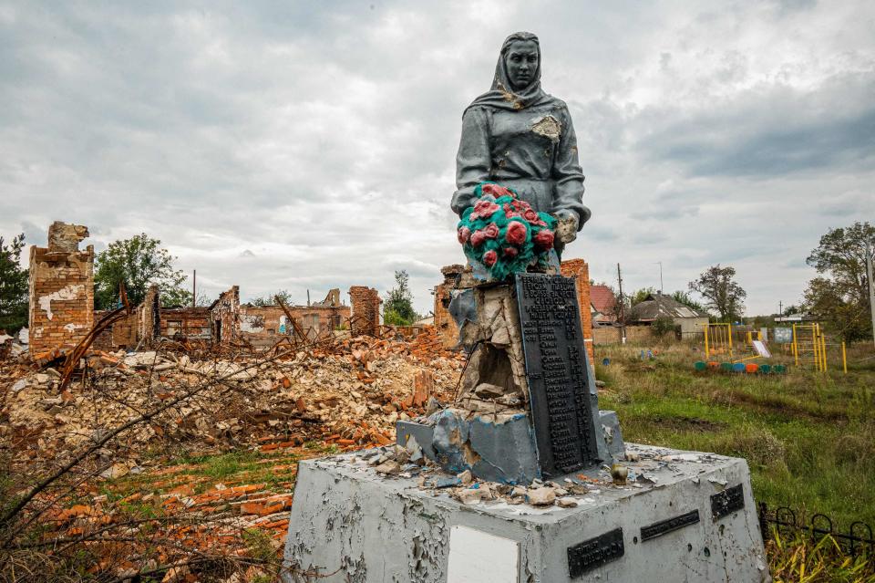 A monument to those who died during the Second World War against the backdrop of a building destroyed during the occupation by Russian troops, in the village of Prudianka, Kharkiv region, amid the Russian invasion of Ukraine.