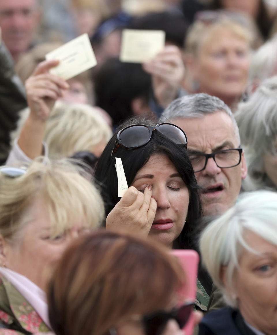 People read aloud names of children as they gather to protest at the site of the former Tuam home for unmarried mothers in County Galway, Sunday, Aug. 26, 2018. Survivors of one of Ireland's wretched mother and baby homes hold their own demonstration Sunday. The location is Tuam, site of a mass grave of hundreds of babies who died at a church-run home. (Niall Carson/PA via AP)